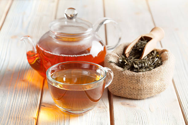 Cup of tea, teapot and tea leaves on wooden table