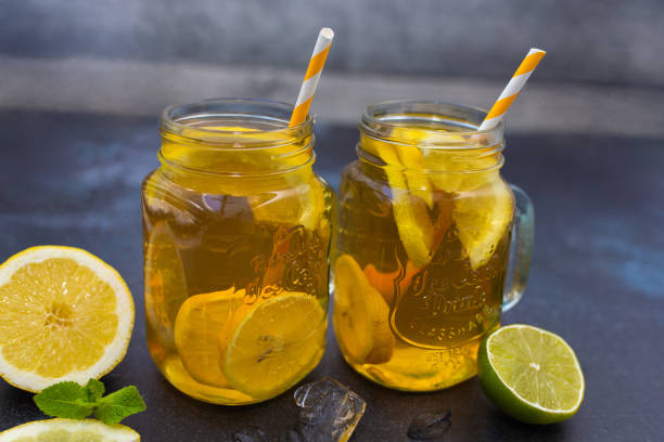 Traditional iced tea with lemon, mint and ice in tall glasses. Dark background.